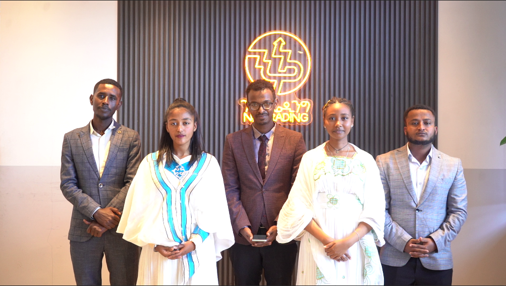 Branding and digital marketing team for NIK Trading, posing in front of their logo in a professional setting.